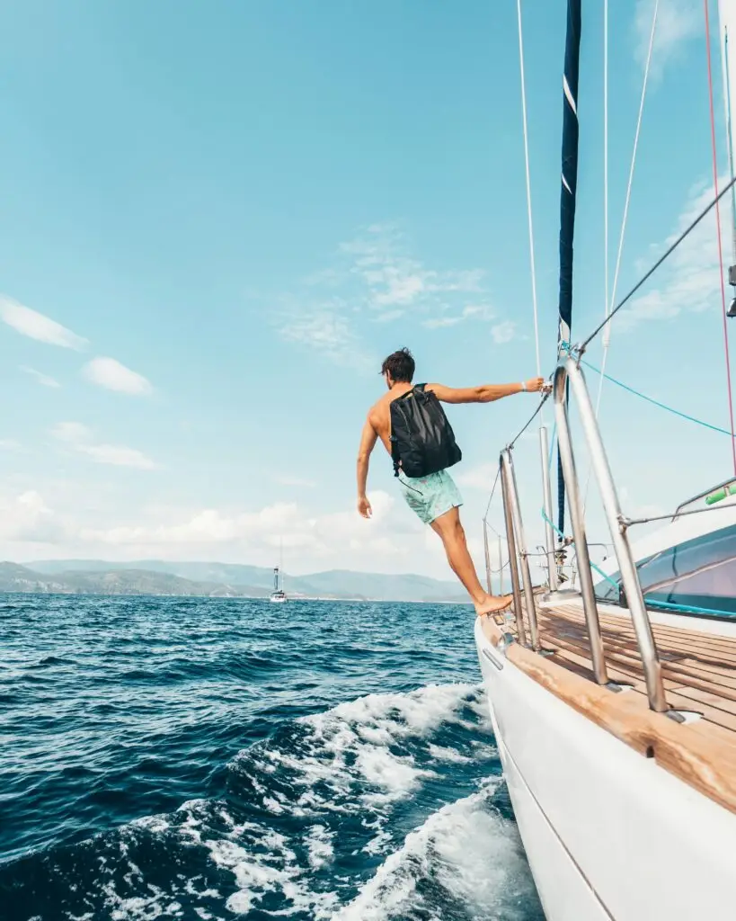 Man sailing in vibrant Greek waters, depicting freedom and adventure under clear skies.